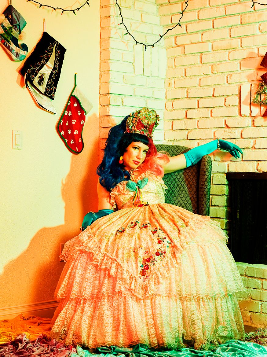 A person in a peach-colored vintage ball gown poses dramatically against a brick wall in a series of photos.