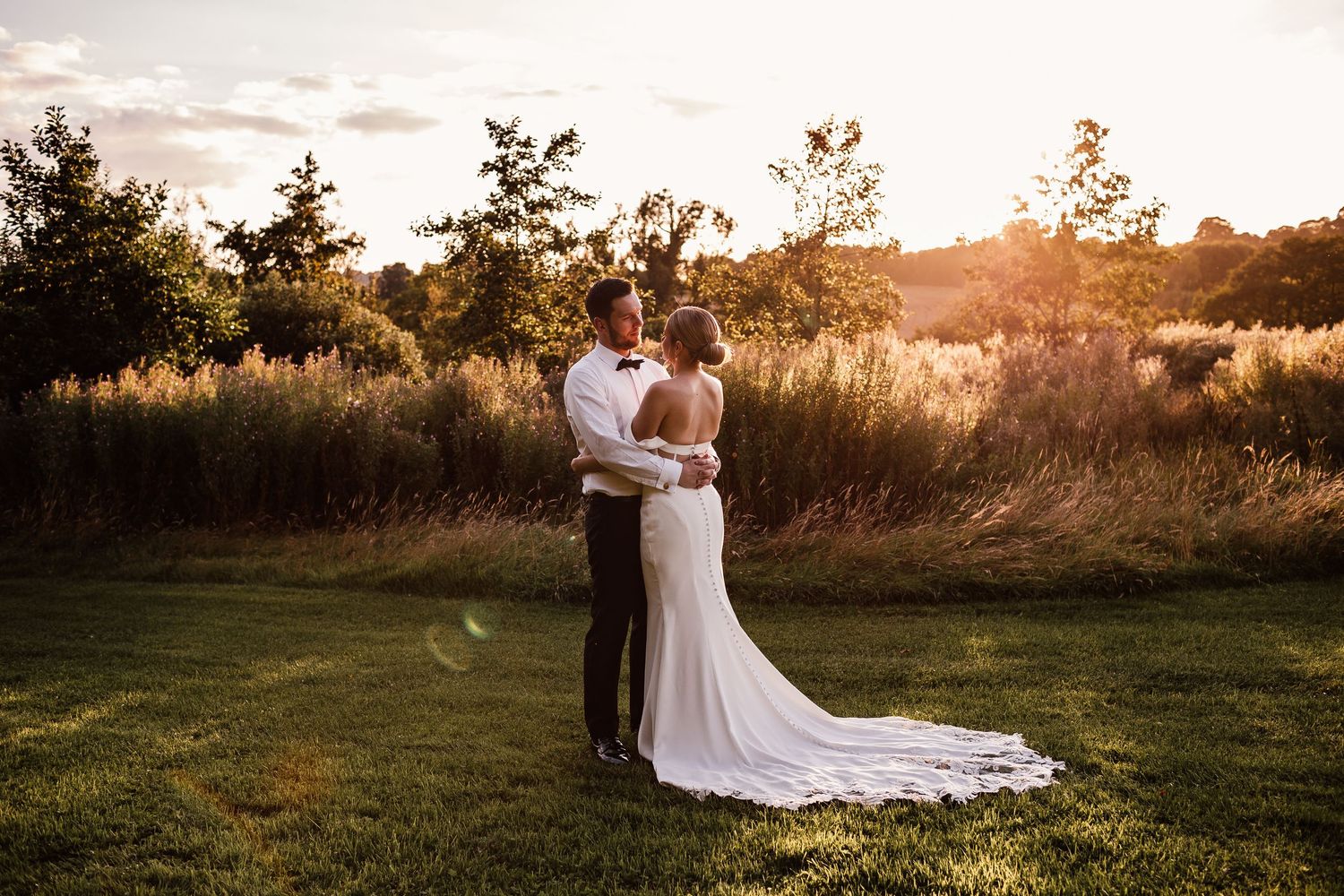 Romantic sunset photo session in a golden field with soft glowing sunlight filtering through trees.