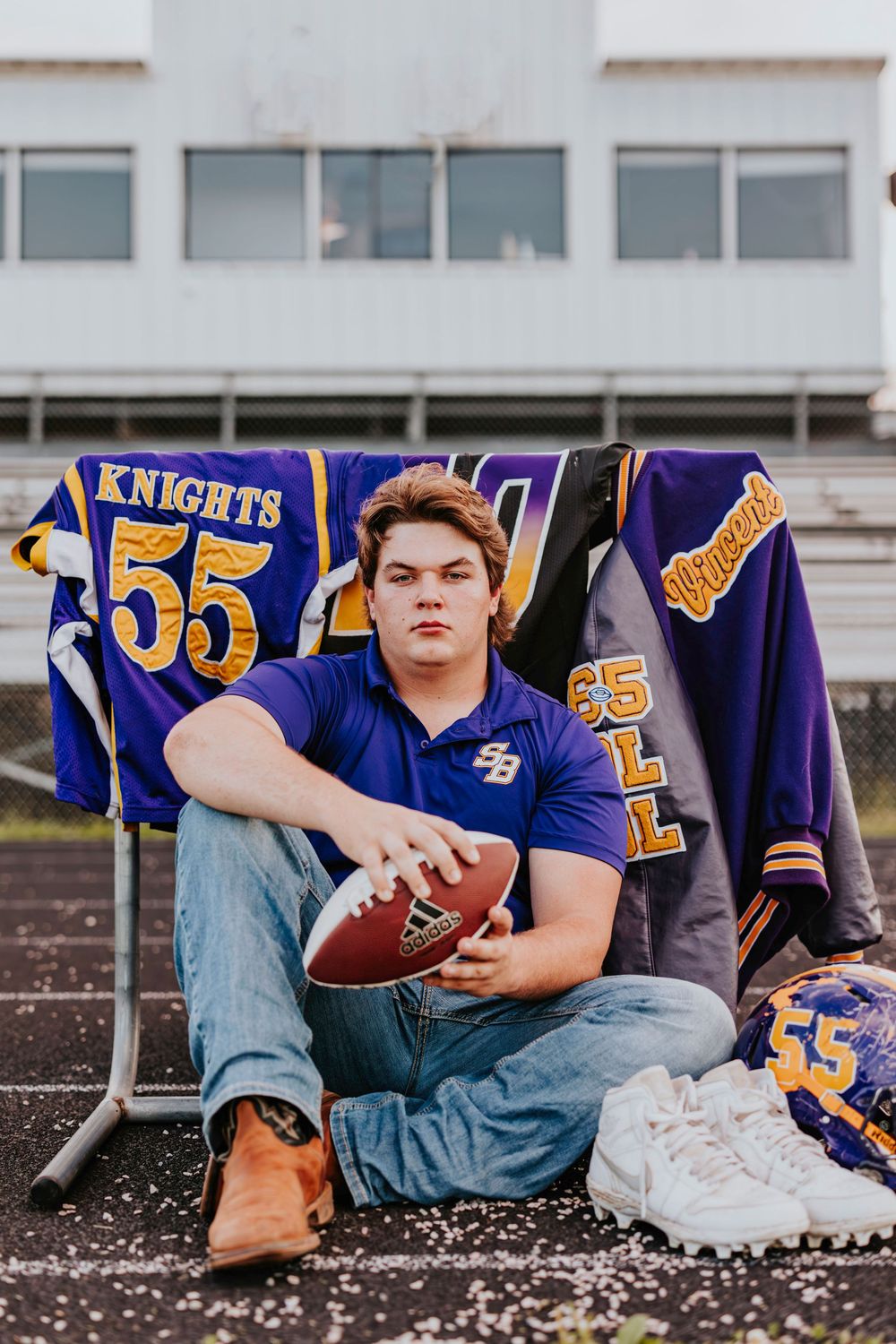 Football player poses with team banners and gear displaying number 55.