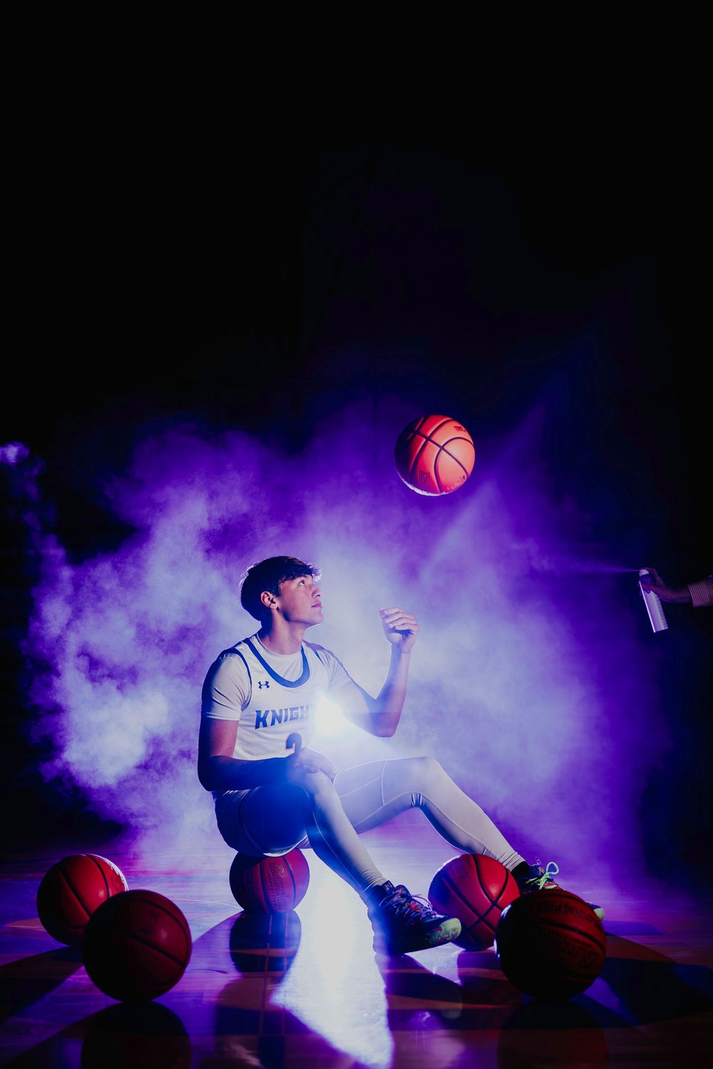 Dynamic basketball action shot with purple smoke effects and floating ball.