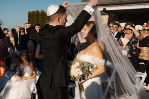 Newlyweds share their first dance surrounded by guests at an outdoor wedding reception during golden hour.