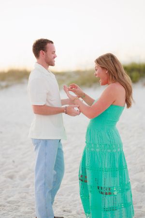 A romantic moment unfolds as a couple dances together on a white sandy beach.
