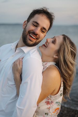 A romantic couple shares intimate moments by the ocean during a sunset photoshoot series.