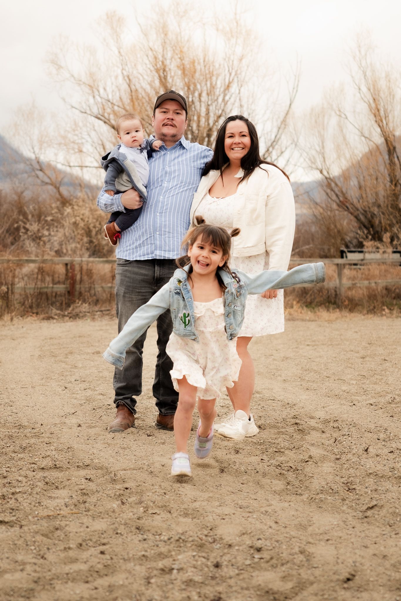Group of people in cream colored sweaters posing among natural landscape.
