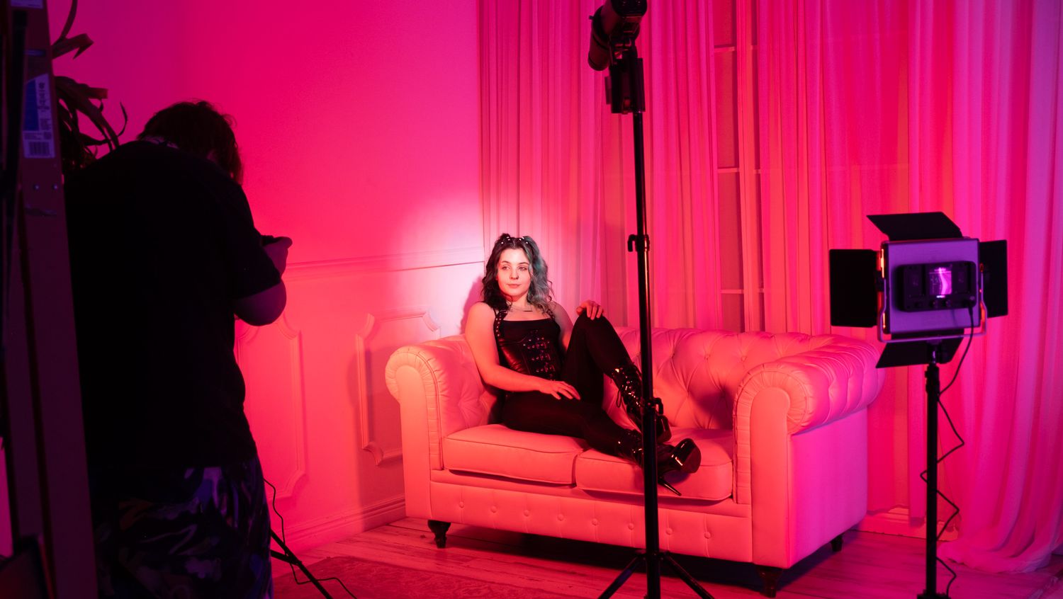 A pink and magenta illuminated interior space with dramatic lighting and modern furniture creates a moody atmosphere.