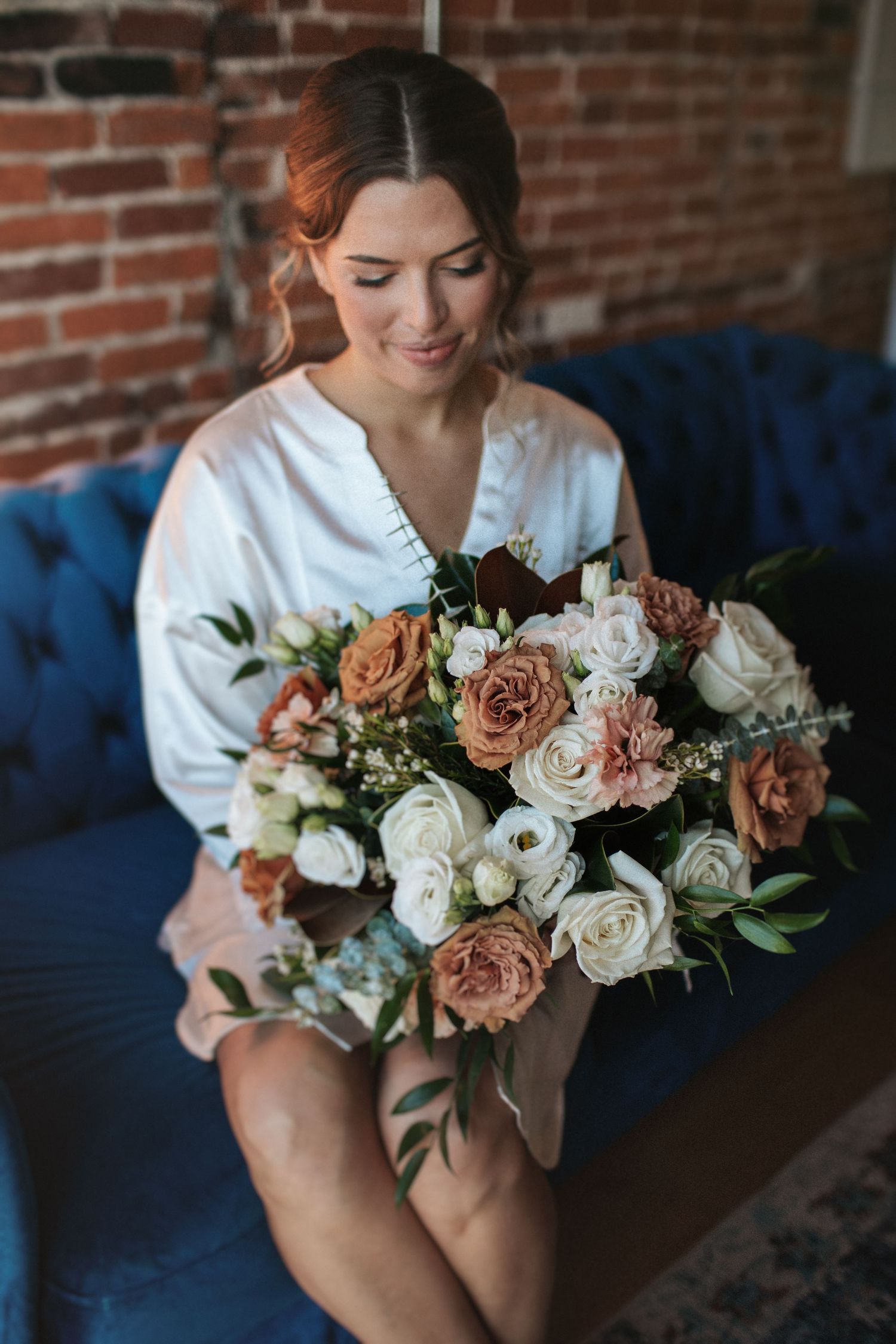 Close-up shots of a romantic bouquet featuring blush and white roses on a blue velvet sofa.