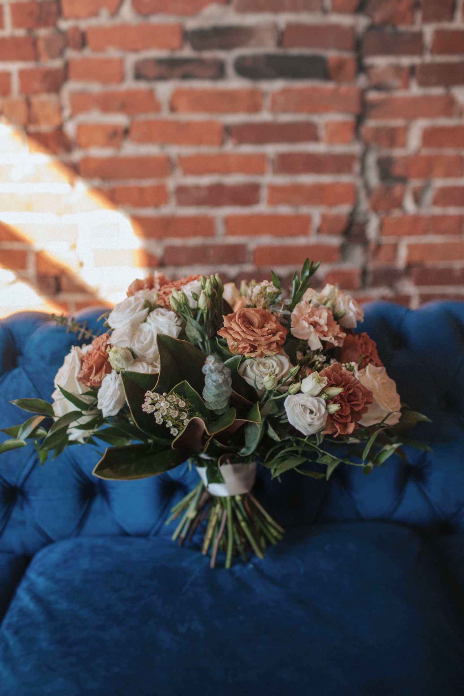 Elegant floral arrangement with peach and white roses displayed on deep blue velvet fabric.