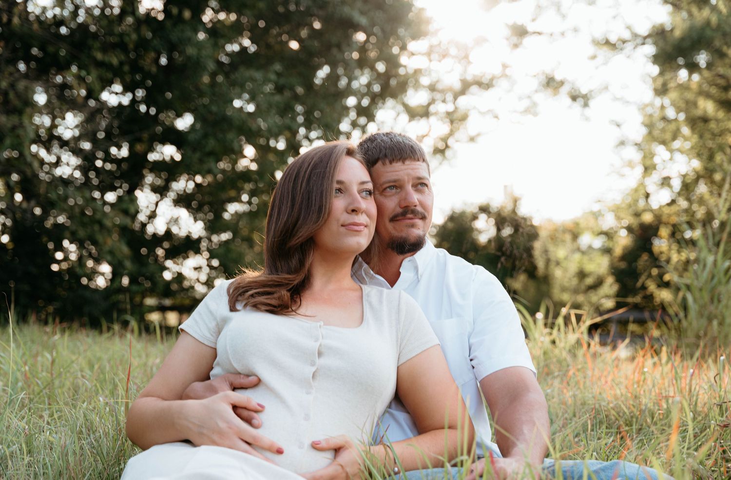 Couple shares tender moment in a sun-drenched meadow during golden hour.