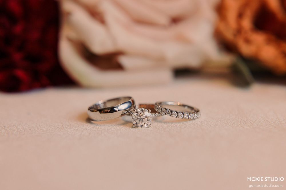 Close-up view of elegant diamond wedding rings on a blush pink surface with soft lighting and shallow depth of field.