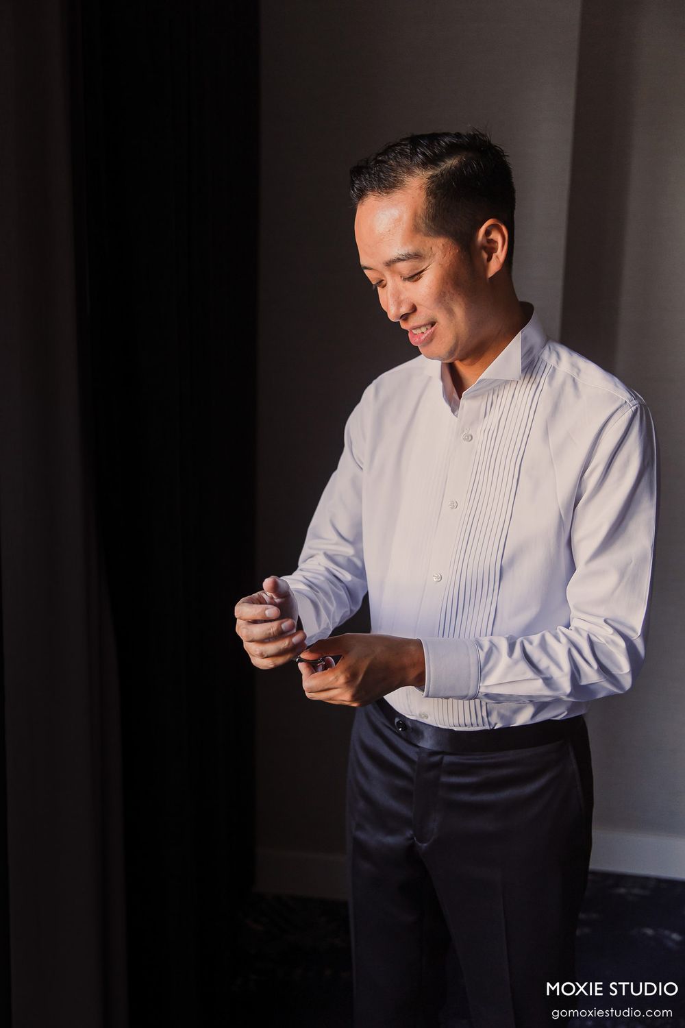 Professional portrait series showing person in white dress shirt looking down at phone in dramatic lighting.