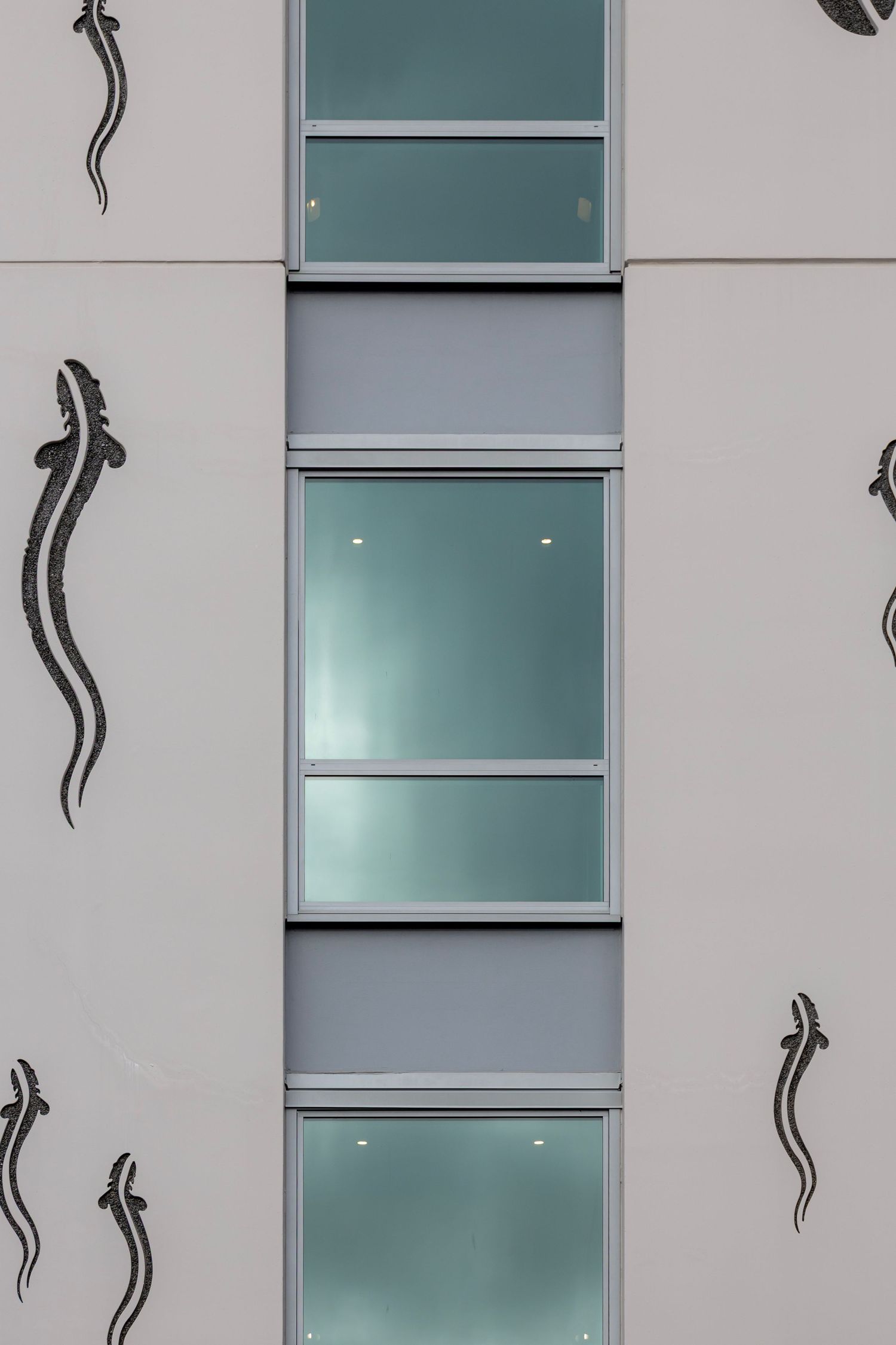 Stylised eel-like illustrations climb vertically between frosted windows on a white multi-storey building.