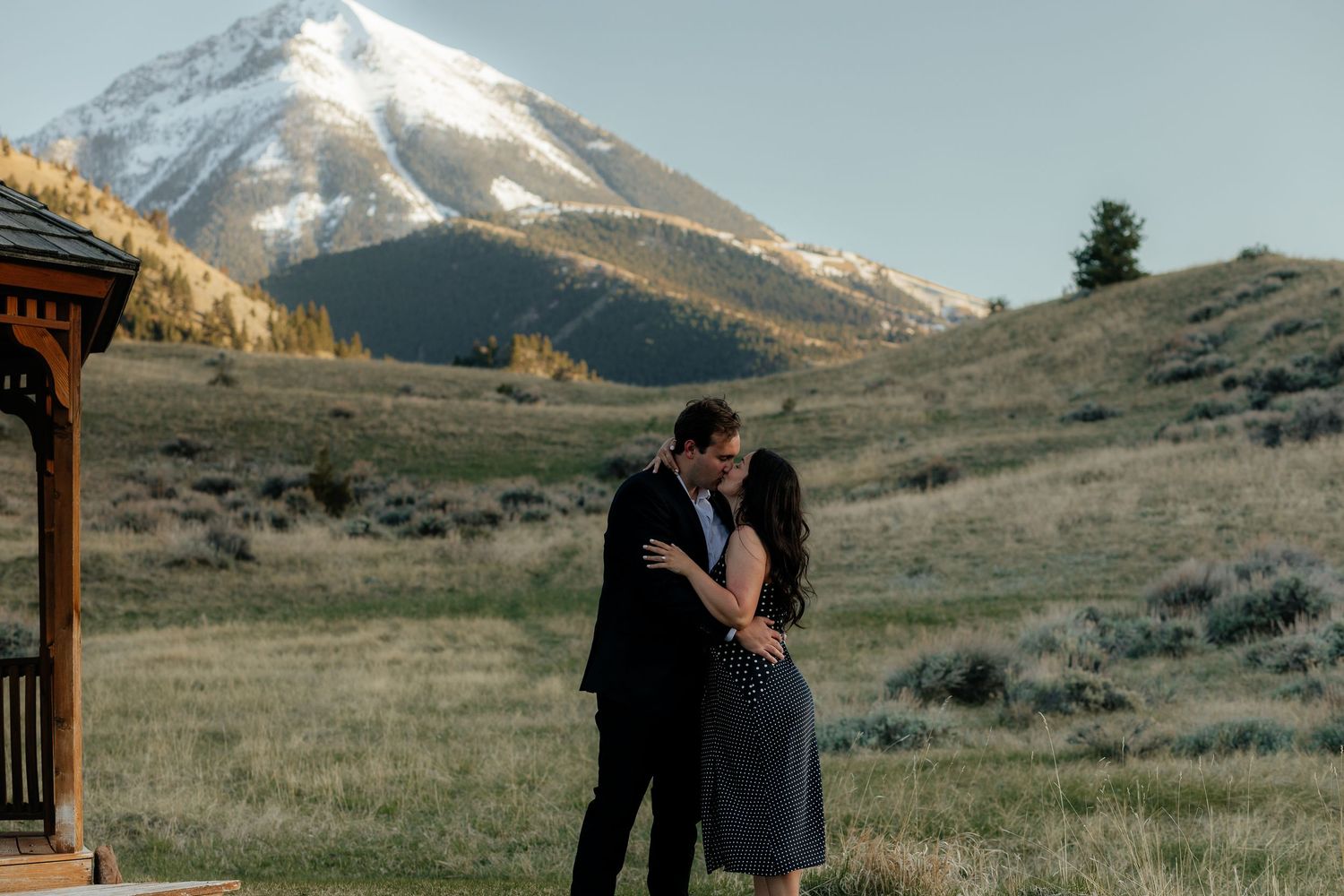 Two hands raise champagne flutes in a celebratory toast against a backdrop of mountains and blue sky.
