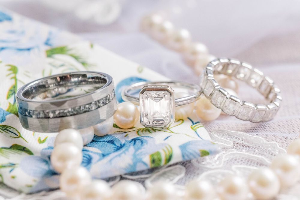 Wedding ring set with pearls and blue floral fabric creating romantic bridal details.