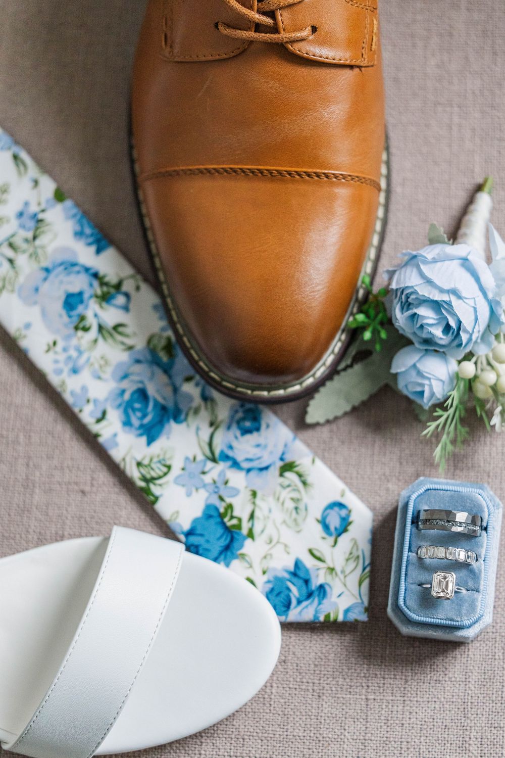 Brown leather dress shoe paired with white bridal sandal and blue floral accessories.