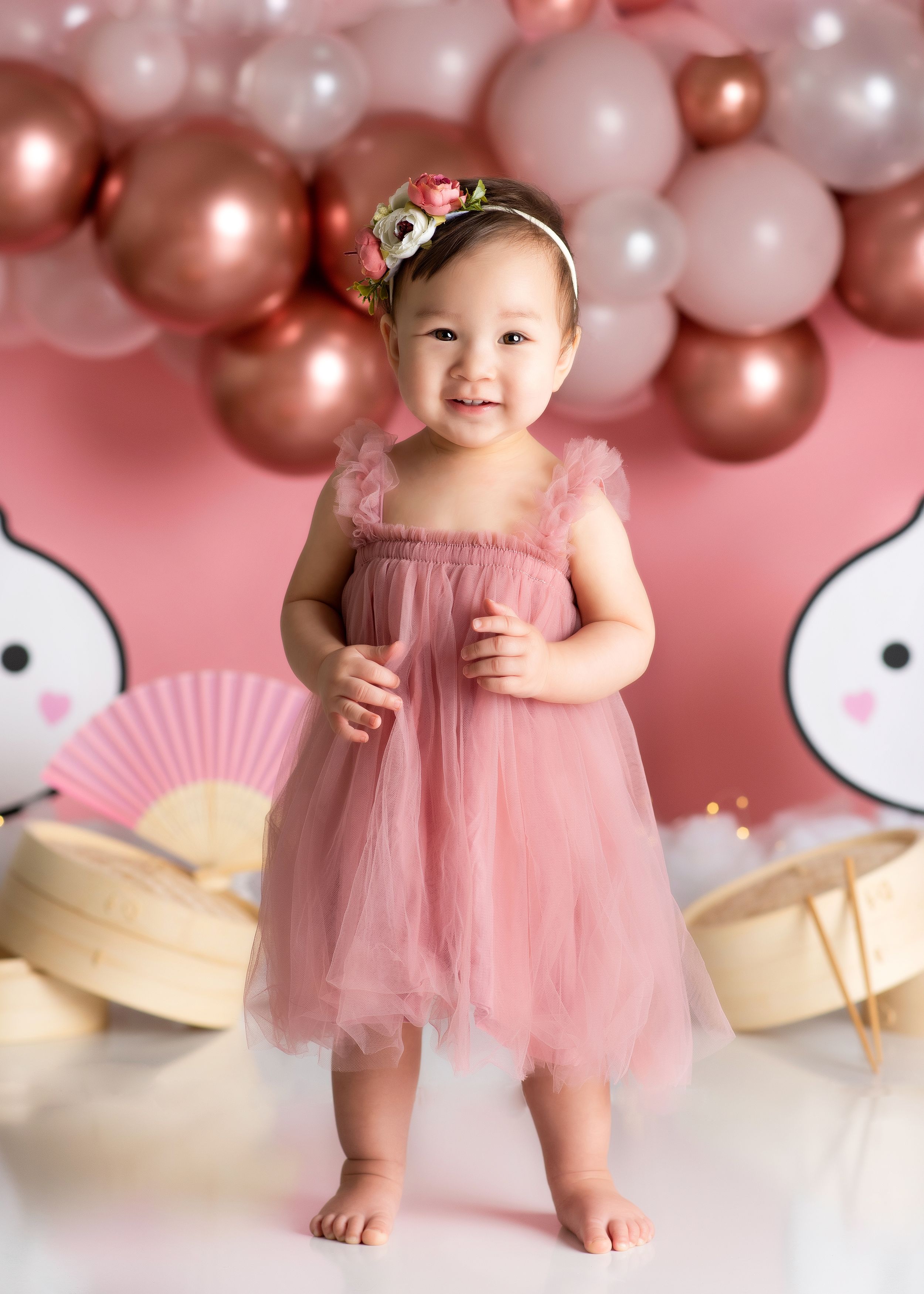 a young girl stands in a dumpling themed studio wearing a pink dress during a shoot with a minneapolis photographer