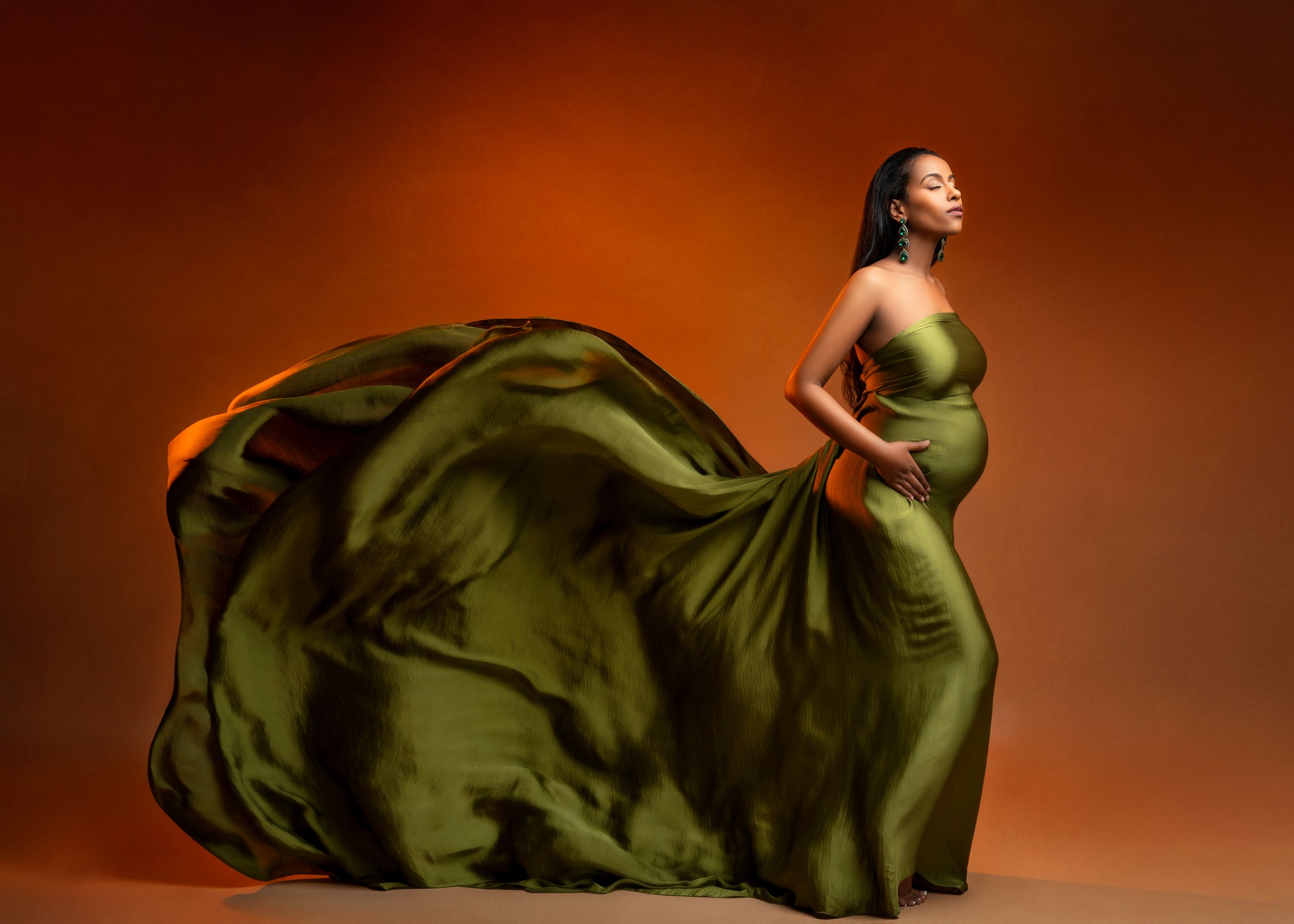 a maternity photo of a woman wearing a flowing green gown by a minneapolis photographer
