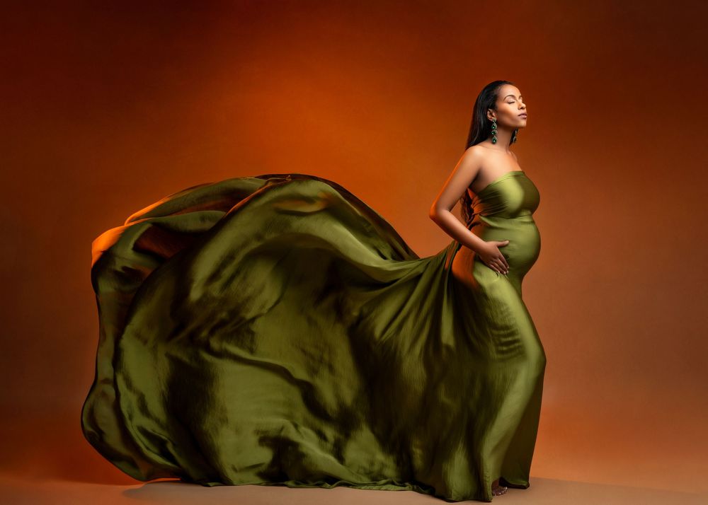 a maternity photo of a woman wearing a flowing green gown by a minneapolis photographer