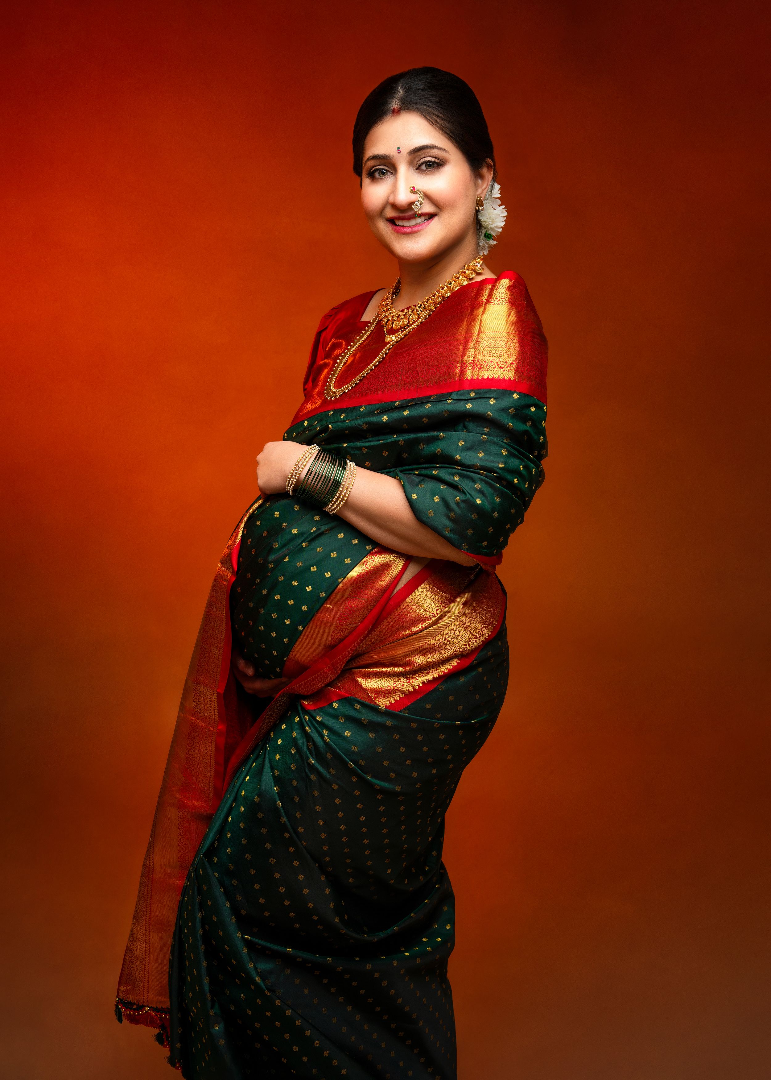 a woman wearing a traditional saree in emerald green and red silk with gold accents photographed by a minneapolis photographer