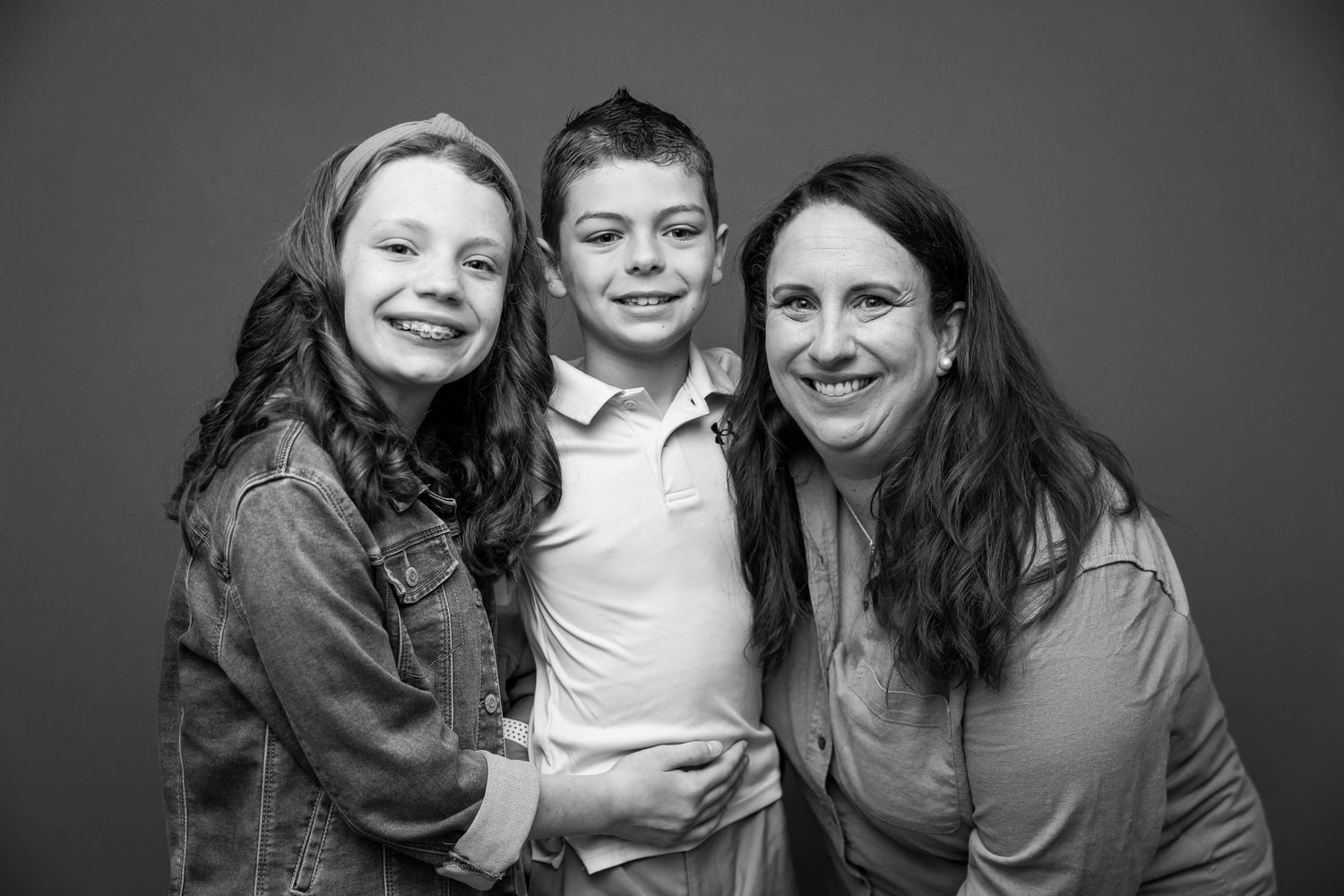 Black and white portrait of three people smiling together in casual clothing.