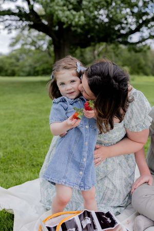 A sweet summer picnic moment with a denim dress and strawberries on a blanket in a green park setting.