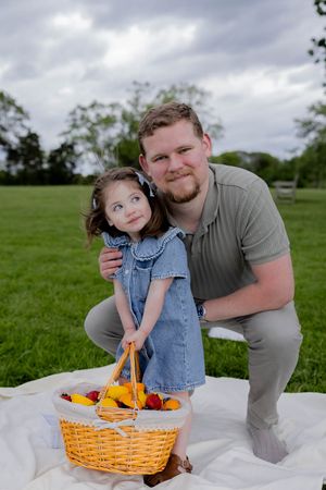 A heartwarming picnic scene with a wicker basket full of fruit on a blanket in a grassy park.