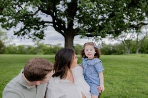 Family enjoying a sunny spring day together on a grassy lawn beneath a large shade tree.