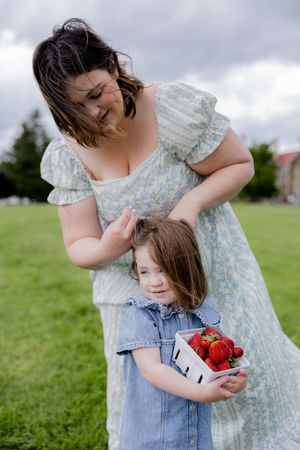 A family picnic moment on a grassy field with a floral dress and denim overalls.