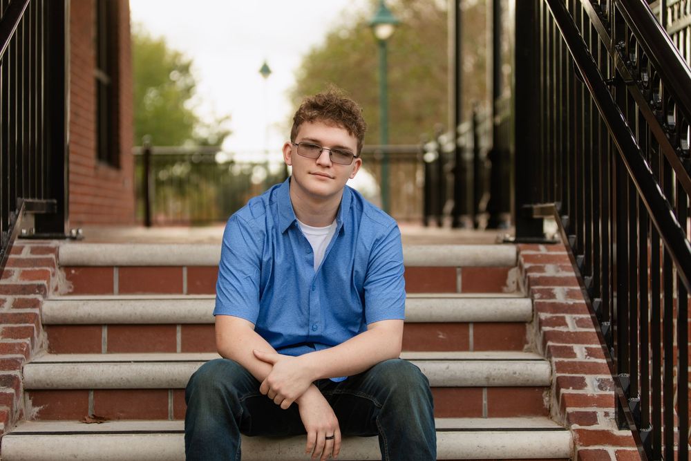 A group of yearbook-style photos arranged horizontally showing the same person in a blue shirt seated on brick steps.