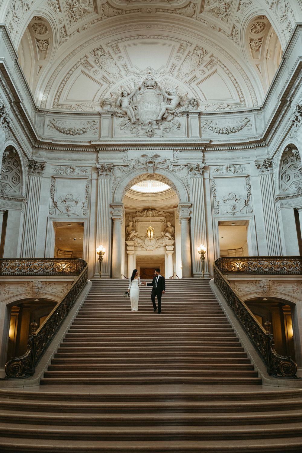 Ornate baroque staircase with white marble steps and elaborate architectural details in a luxurious historic building.