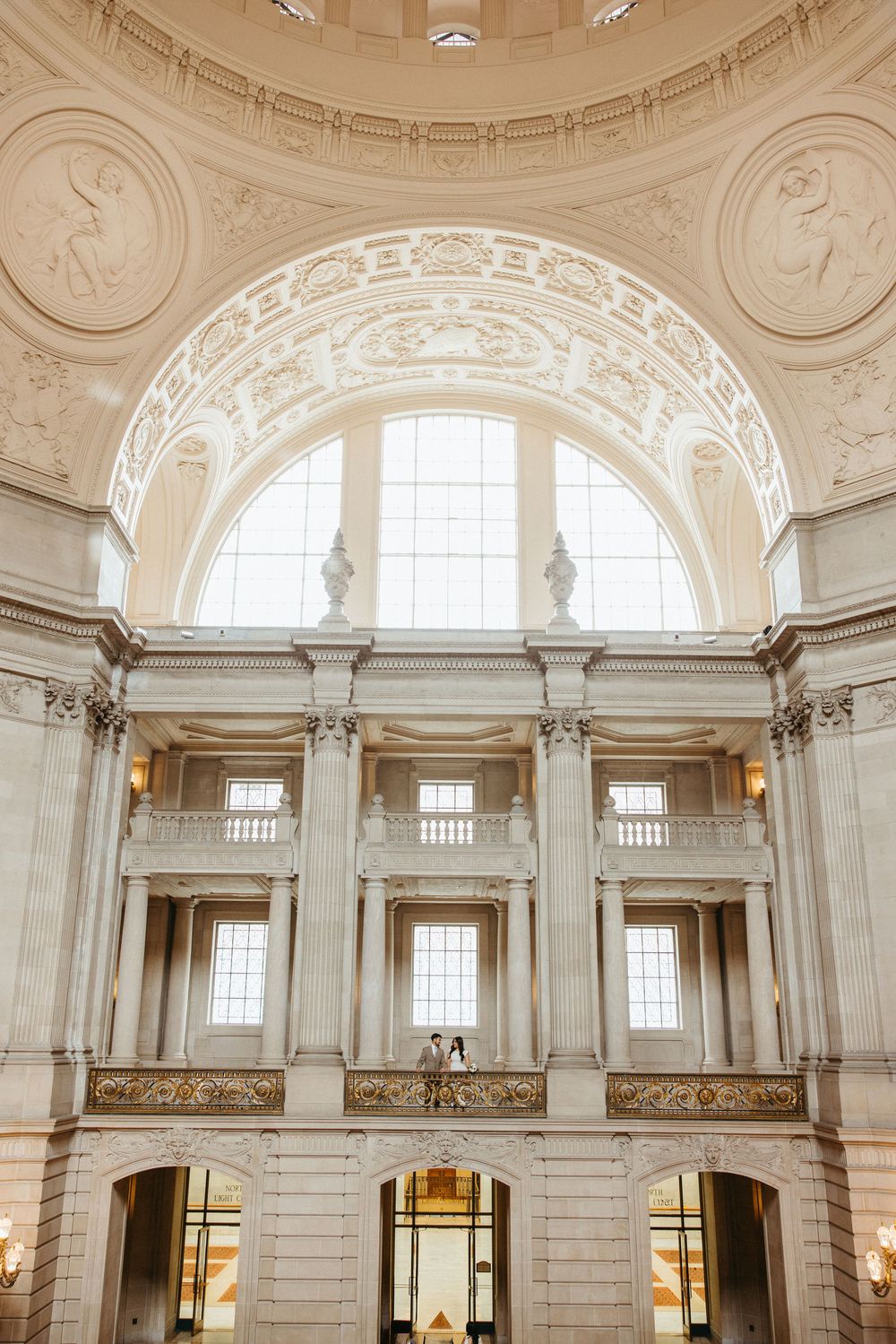 Grand neoclassical rotunda interior with ornate columns, arched windows, and intricate plasterwork ceiling details.