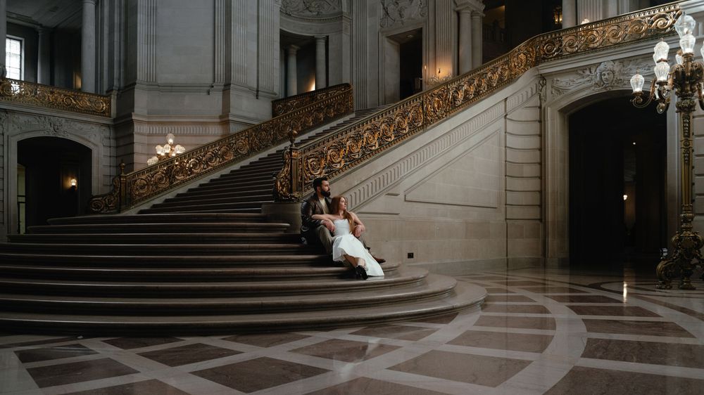 Panoramic view of an ornate marble staircase with gold railings inside a grand historic building.