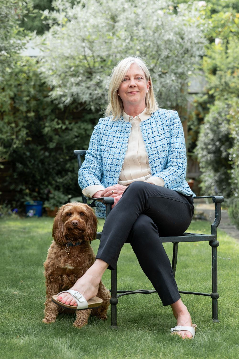 A casual photoshoot in a spring garden shows a warm interaction with a brown cocker spaniel dog on an outdoor bench.