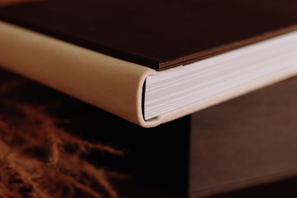 Close-up detail of a book binding showing the spine and pages in warm lighting.