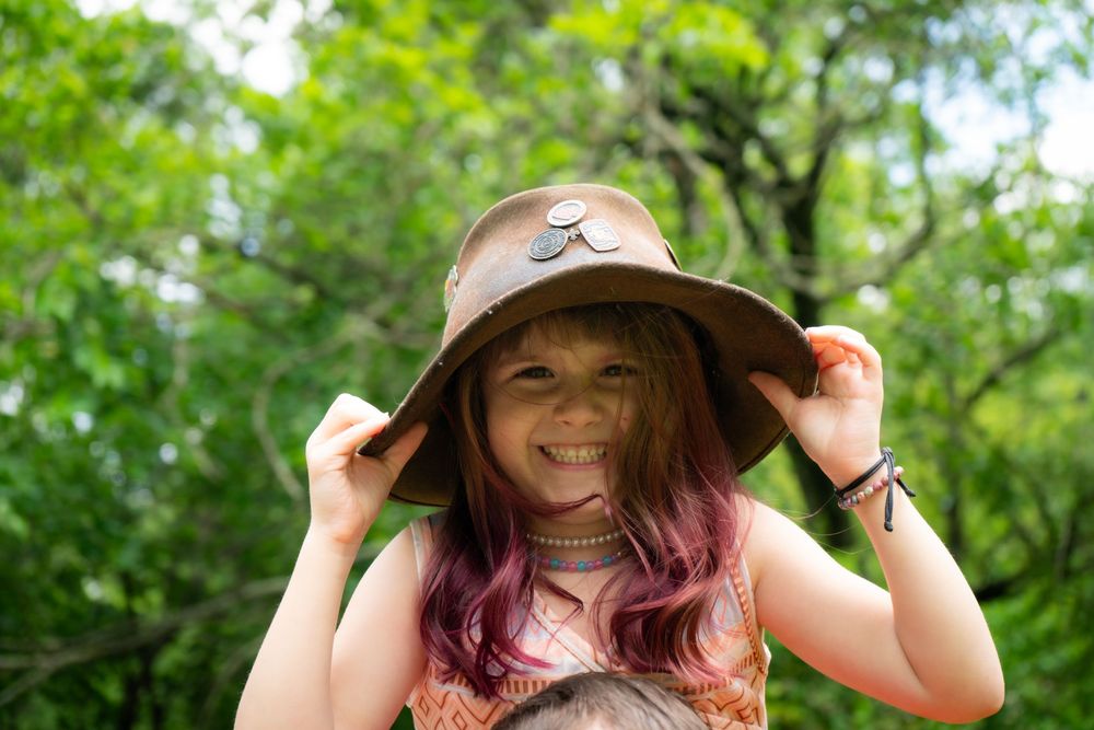 Someone in a floppy sun hat enjoys a peaceful moment in a lush green garden on a sunny summer day.