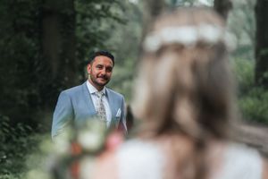A bride and groom share an intimate moment in a lush garden setting, surrounded by soft bokeh effect.