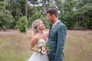 Romantic wedding portraits of couple posing in a sunlit field with wildflowers.