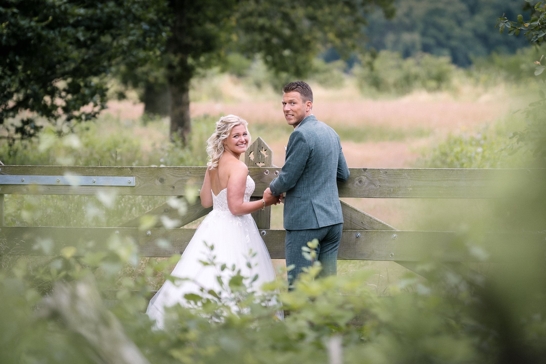 Scenic outdoor wedding photography session in a meadow with greenery and trees.