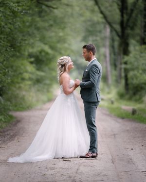 Romantic wedding portraits captured on a tree-lined dirt path in the forest.