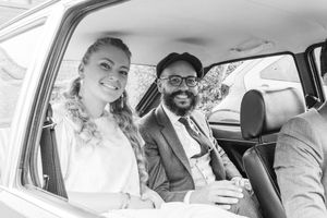 Black and white photos of newlyweds sharing joyful moments in their wedding car.