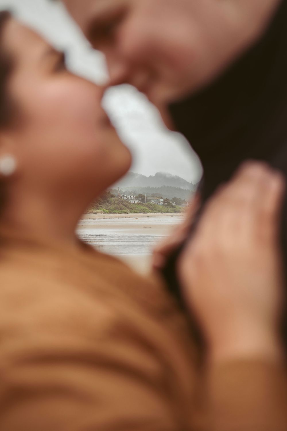 A romantic seaside view framed through an intimate close-up moment against a blurred coastal background.