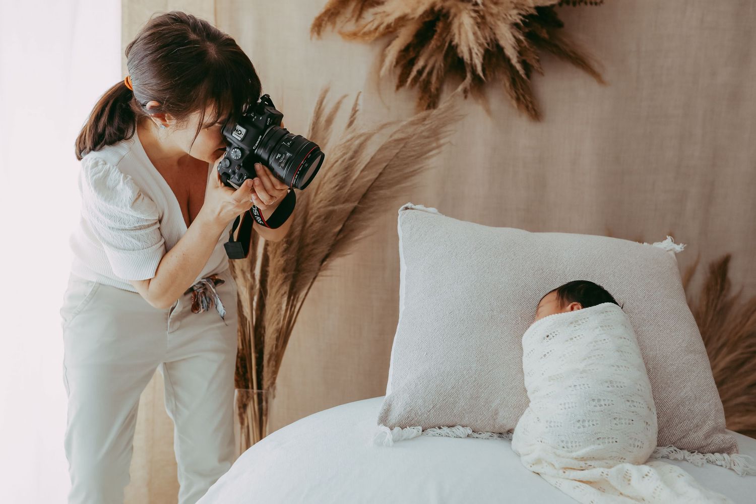 Professional photo shoot setup in minimalist white room with decorative elements.