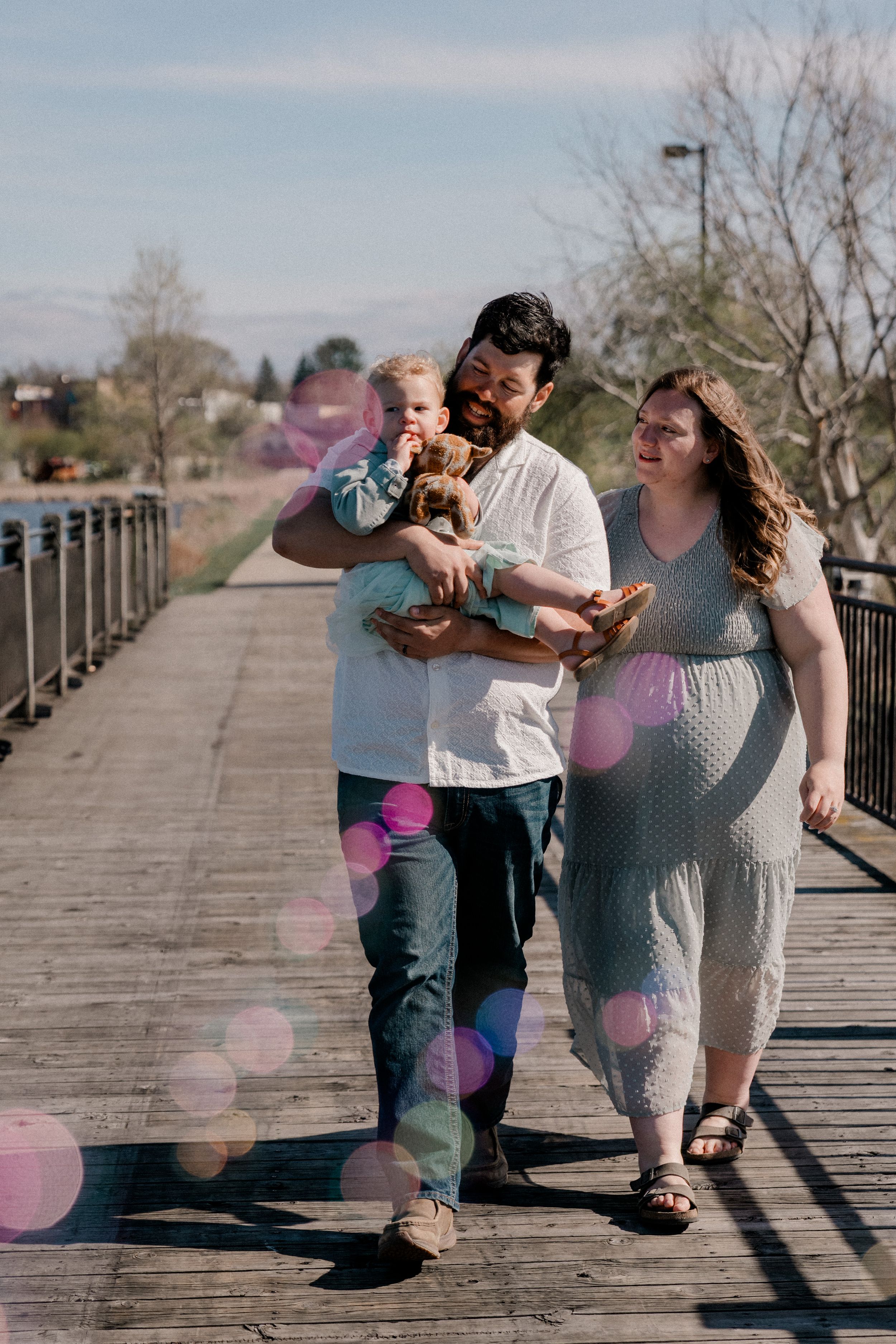 A loving family shares playful moments together on a wooden boardwalk during an outdoor photo session.