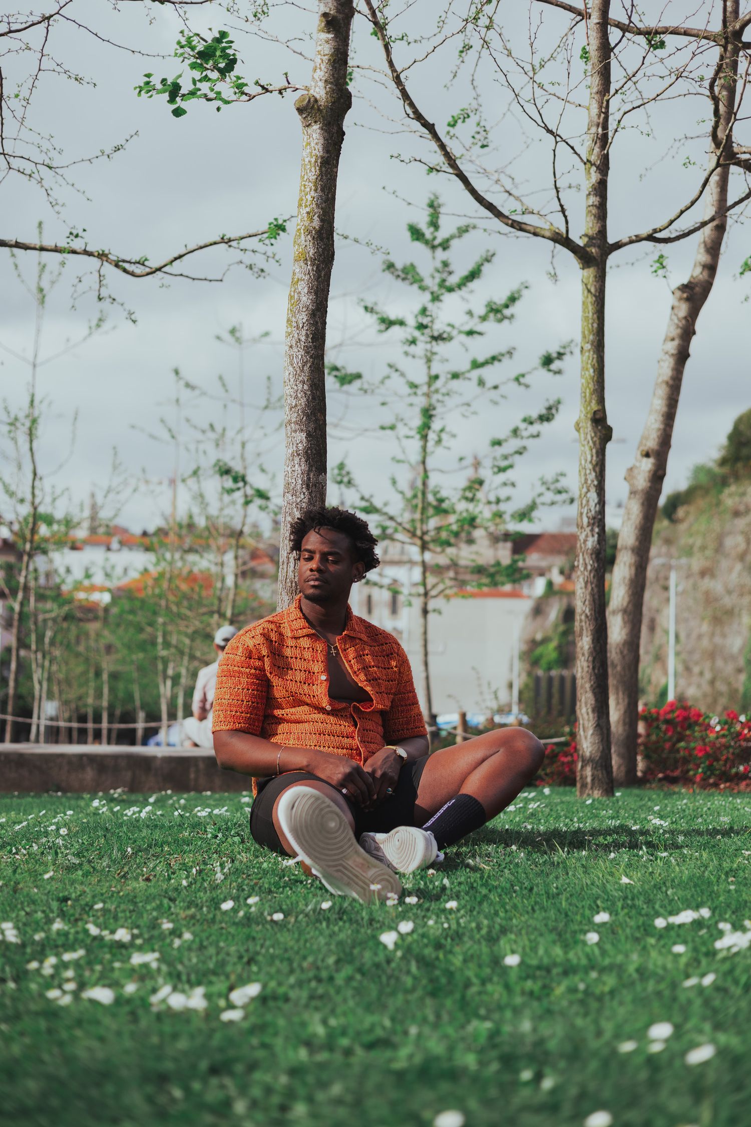 Casual outdoor photoshoot on grass with spring trees in background.