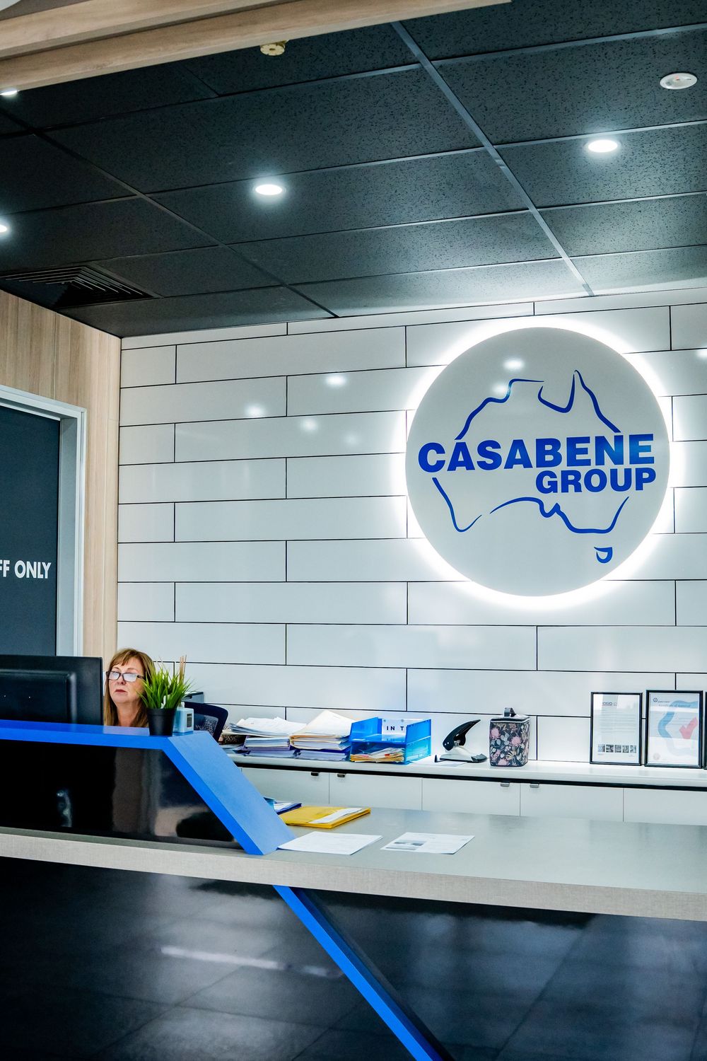 Modern office reception area with illuminated signage and sleek white tile walls.