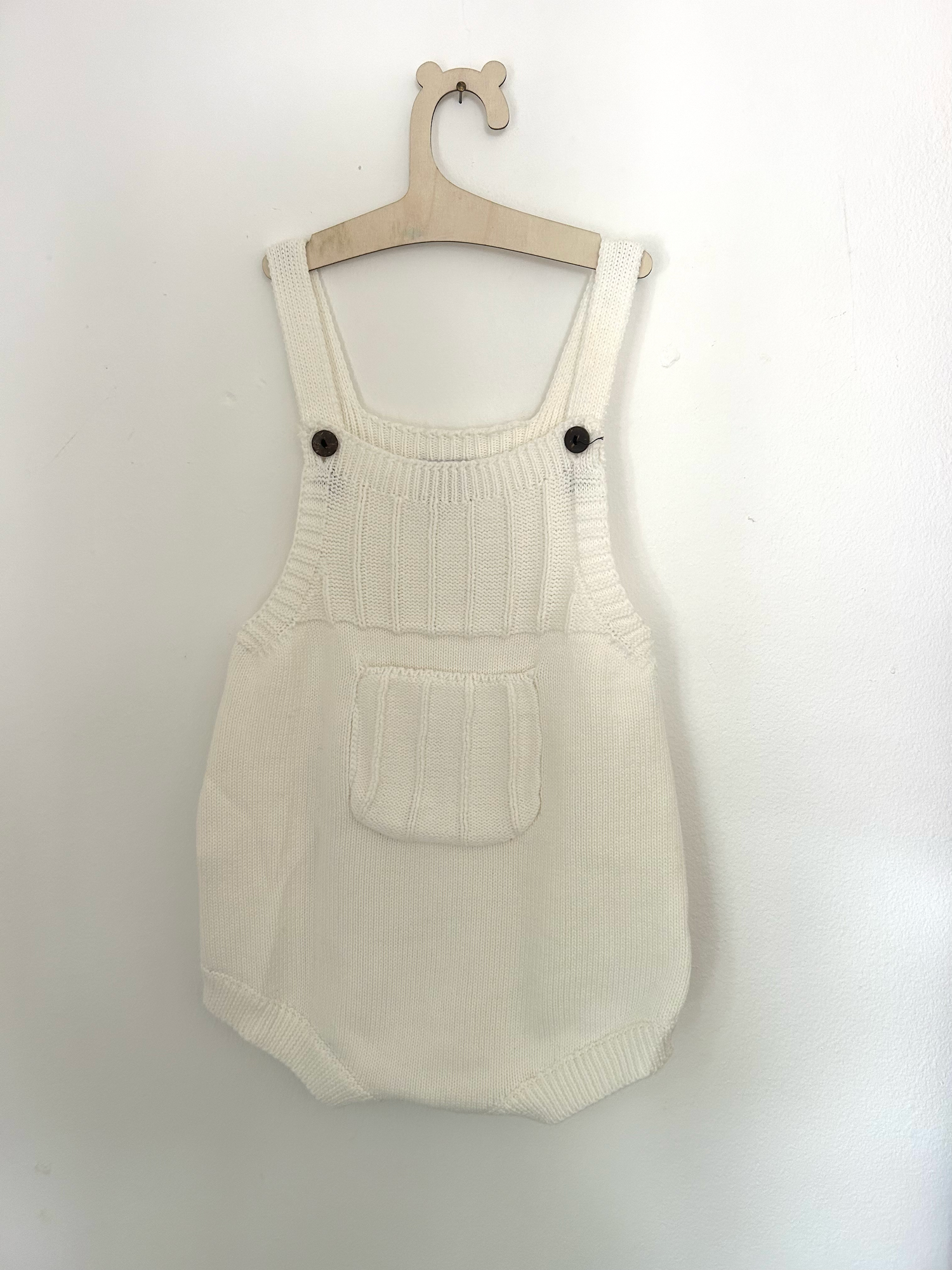 White baby romper with delicate pink embroidered floral design and ruffle details on straps.