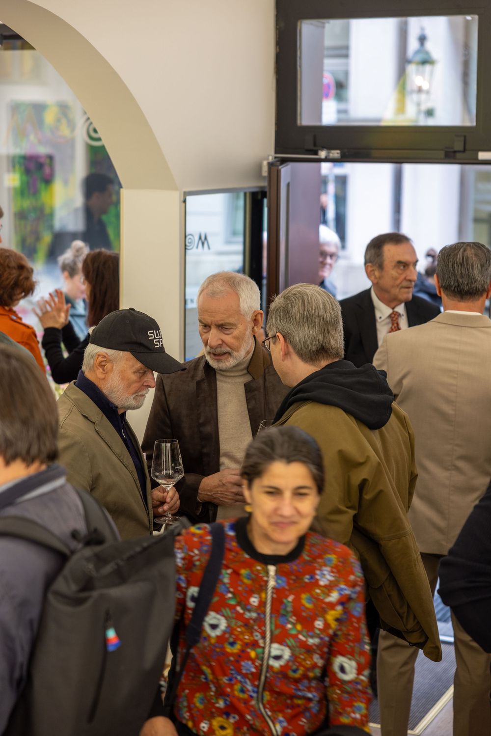 Art gallery opening with crowd mingling and viewing exhibitions.