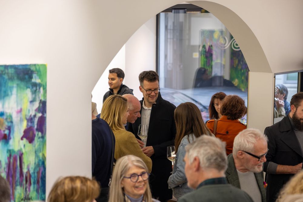 Art gallery visitors mingle beneath arched doorways during an opening reception.
