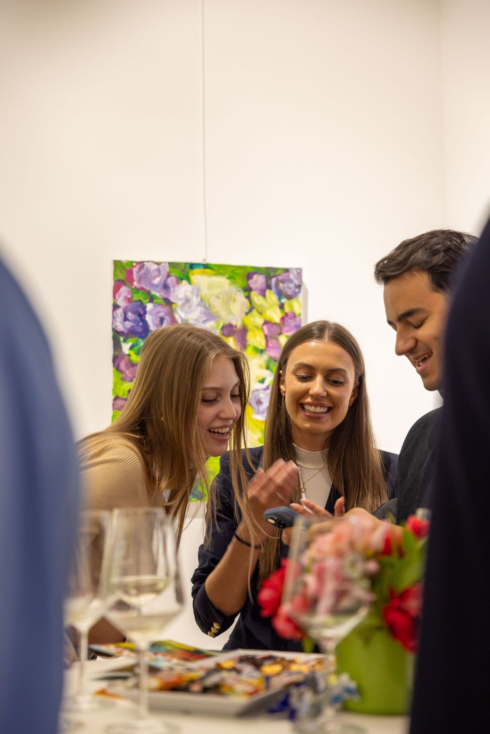 Group shares laughter and conversation during art gallery reception.