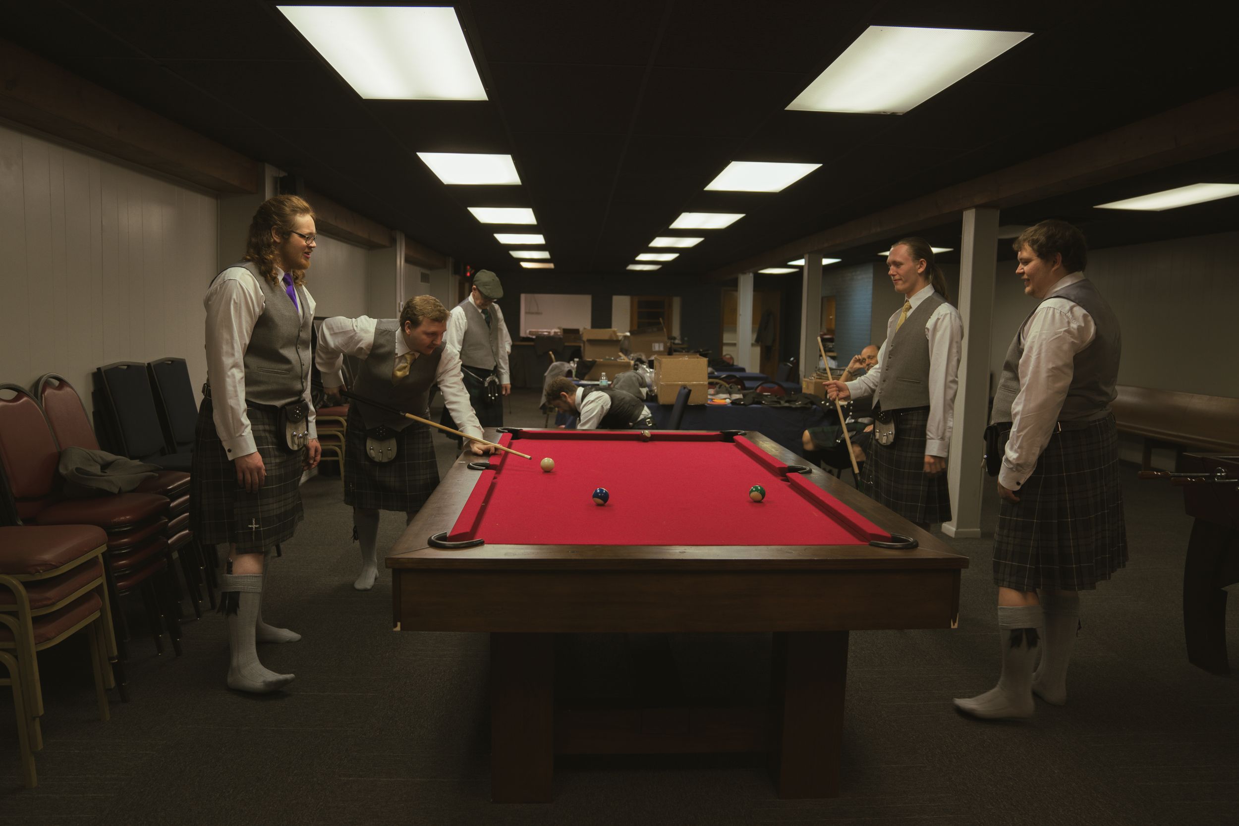 Interior of a dimly lit recreation room with pool tables and fluorescent lighting.