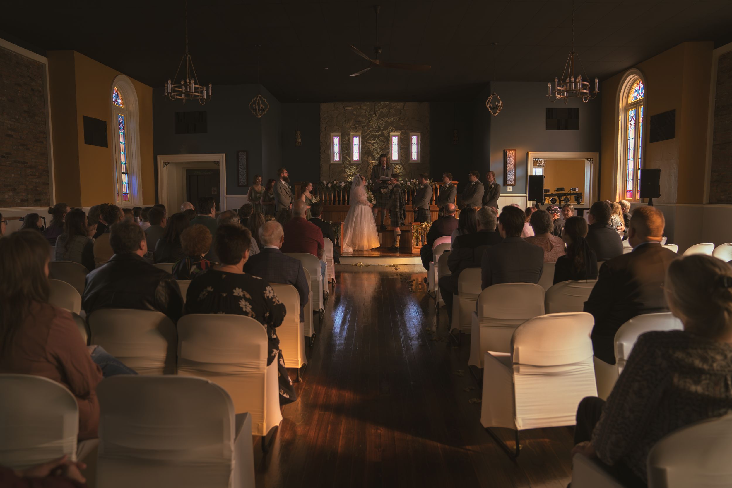 Wide view of a wedding reception venue with guests gathered in a warmly lit space.